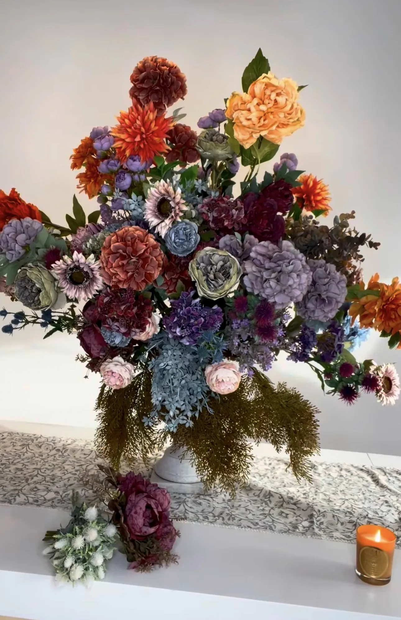 Composición floral de gran formato en tonos morado, naranja y burdeos
